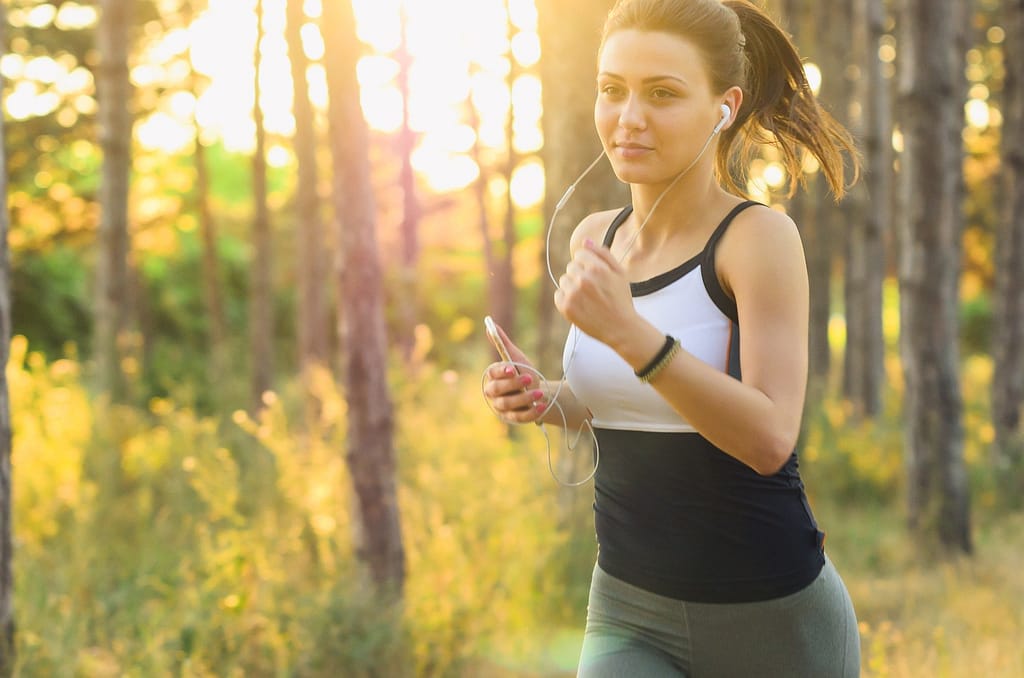 Young woman participating in aerobic exercise by running in the woods 