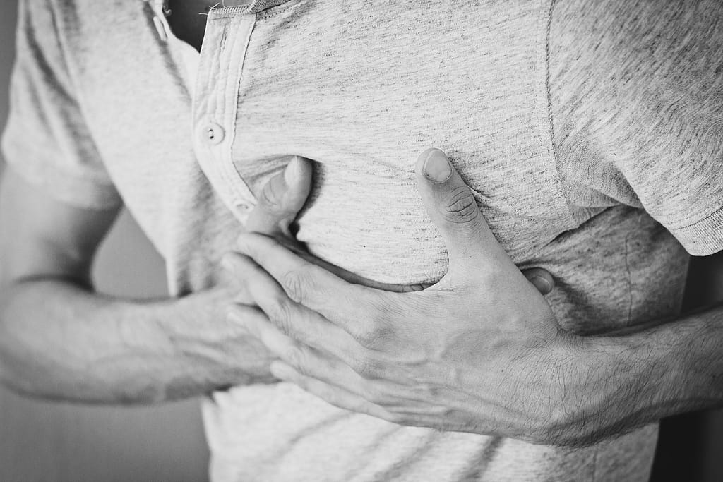 A man holding his chest because of chest pains. This can indicate a heart attack in progress.