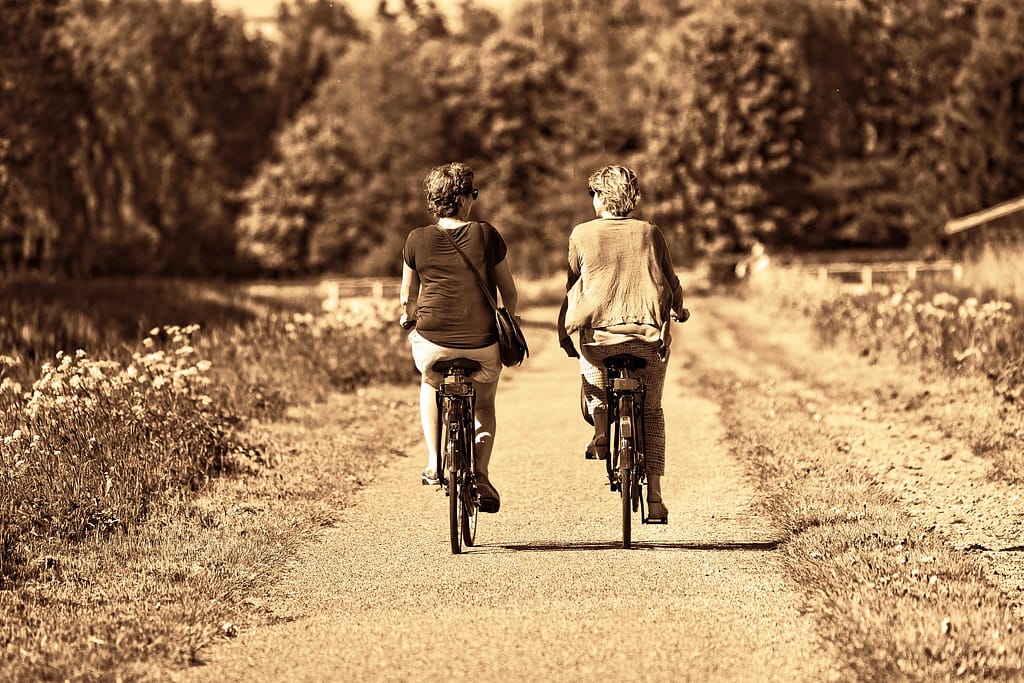 Two women bicycling on a trail. Bicycling is aerobic exercise
