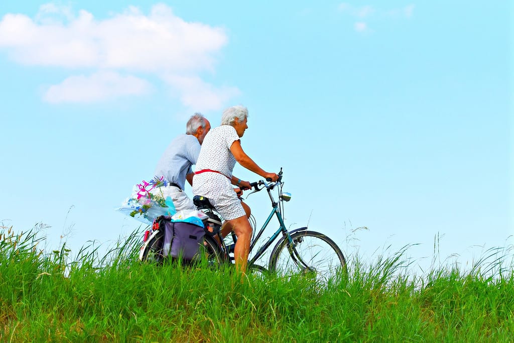 Older couple biking for exercise. It's important to know what the benefits and risks of exercise are, particularly as you age.
