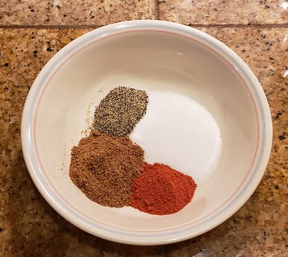 Bowl with ground pepper, cumin powder, cayenne pepper and salt
