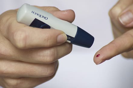 Diabetes represented by someone testing themselves with a glucose meter