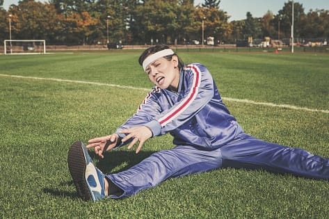 A girl stretching on the field as part of her cool-down